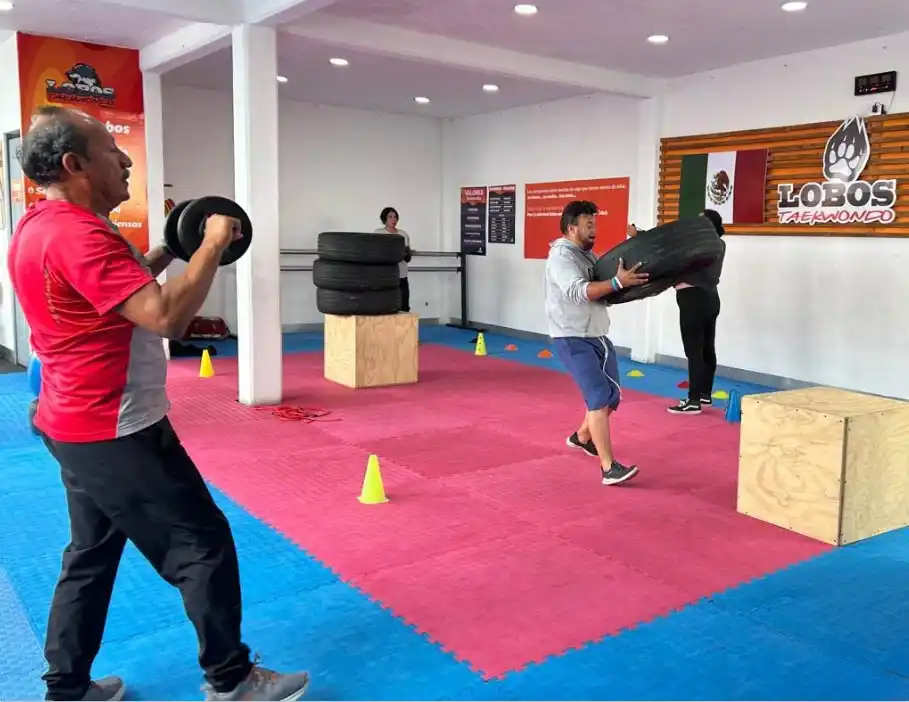 Adultos realizando entrenamiento funcional con pesas y neumáticos en clases de acondicionamiento físico en Lobos TKD Pachuca