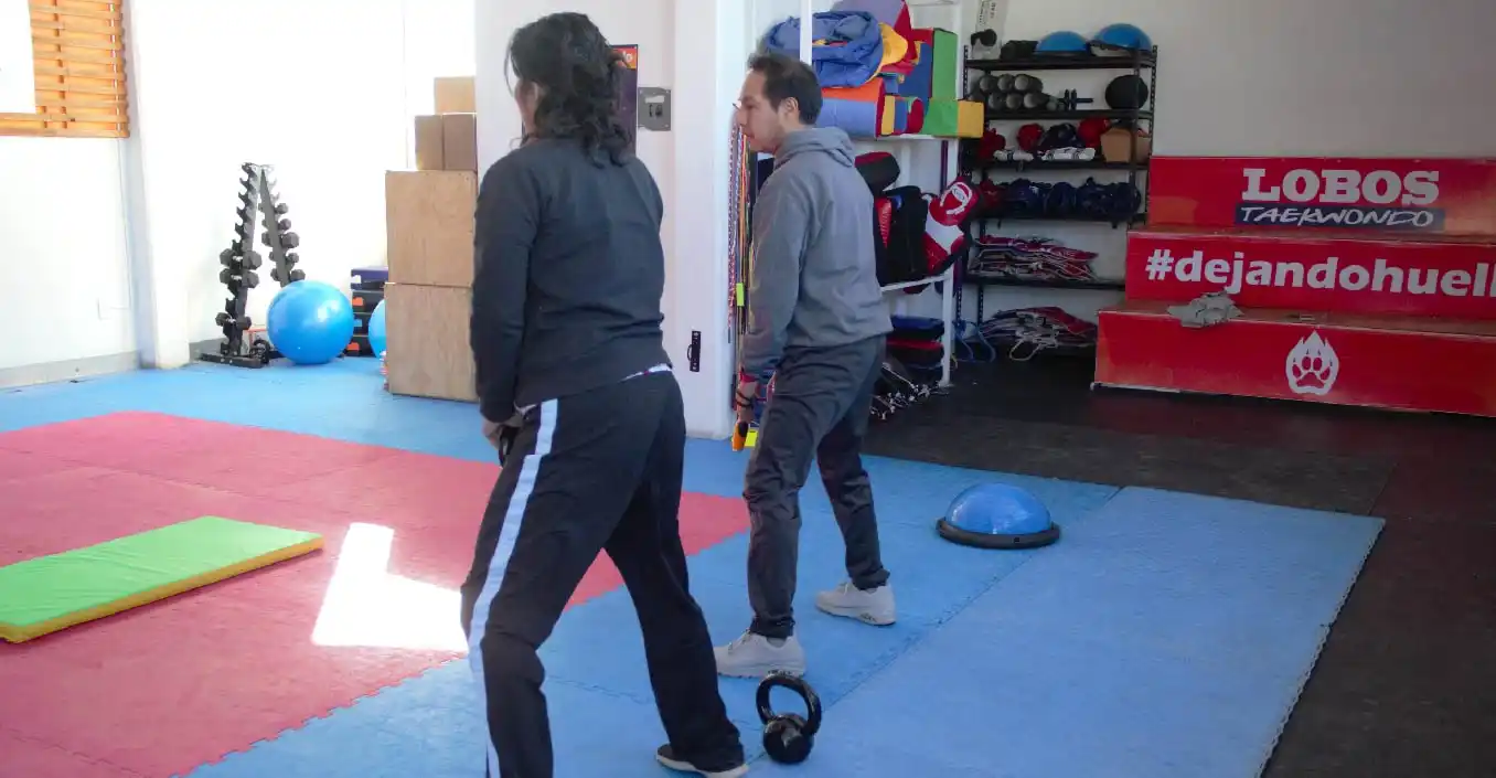 Adultos realizando acondicionamiento físico con pesas rusas en Lobos TKD Pachuca