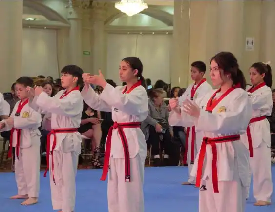 Grupo de jóvenes con cinturón rojo practicando técnicas de Taekwondo en Lobos TKD Pachuca frente al público